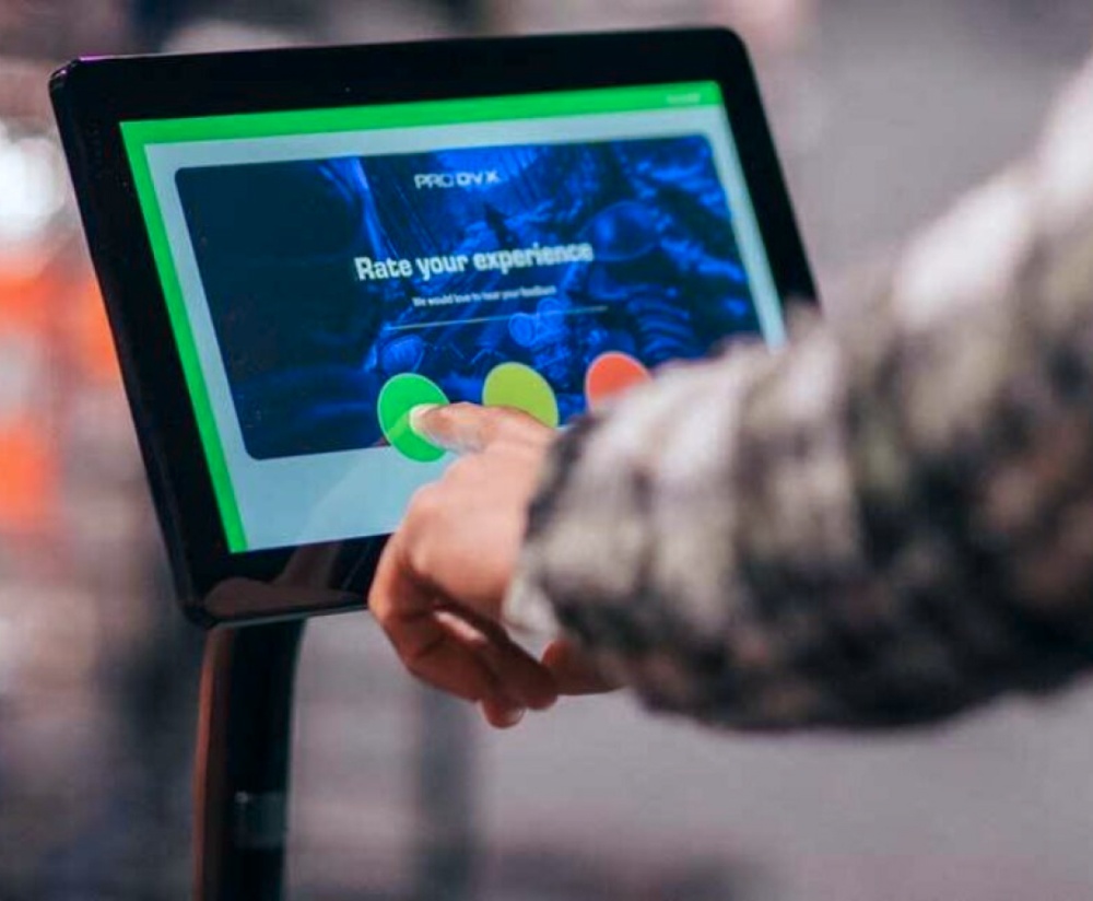 A person selects a rating on a touchscreen display with three colored options: red, yellow, and green.