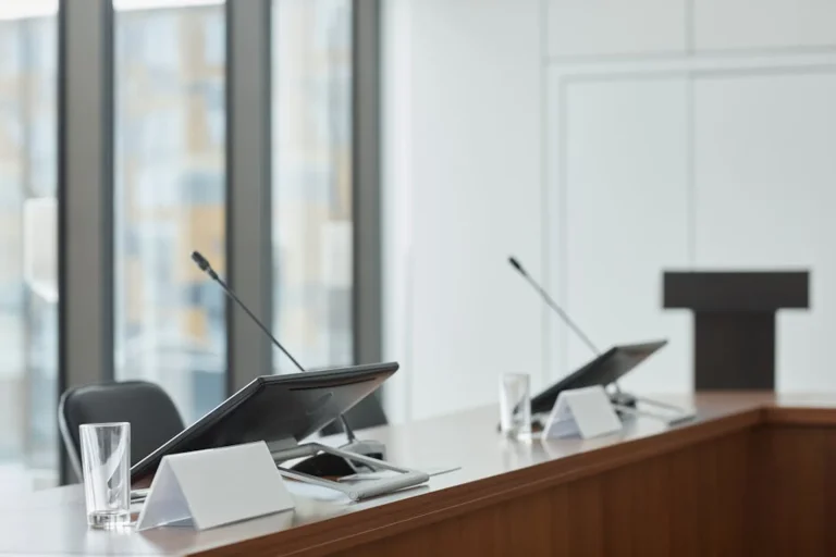Modern executive boardroom featuring minimalist design with integrated AV technology, microphones, and monitors demonstrating Arthur Holm's retractable solutions