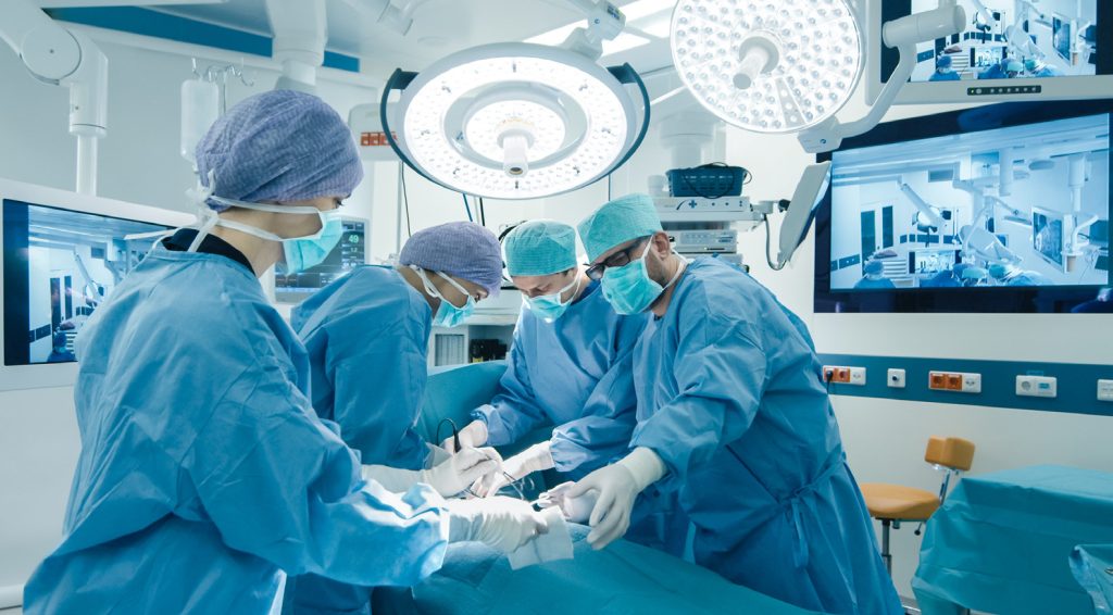 Surgical team operating in a modern theatre with boom mounted displays fed by Cleerline SSF fibre