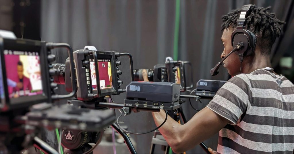 Professional videographer adjusting Marshall camera equipment in corporate broadcast studio
