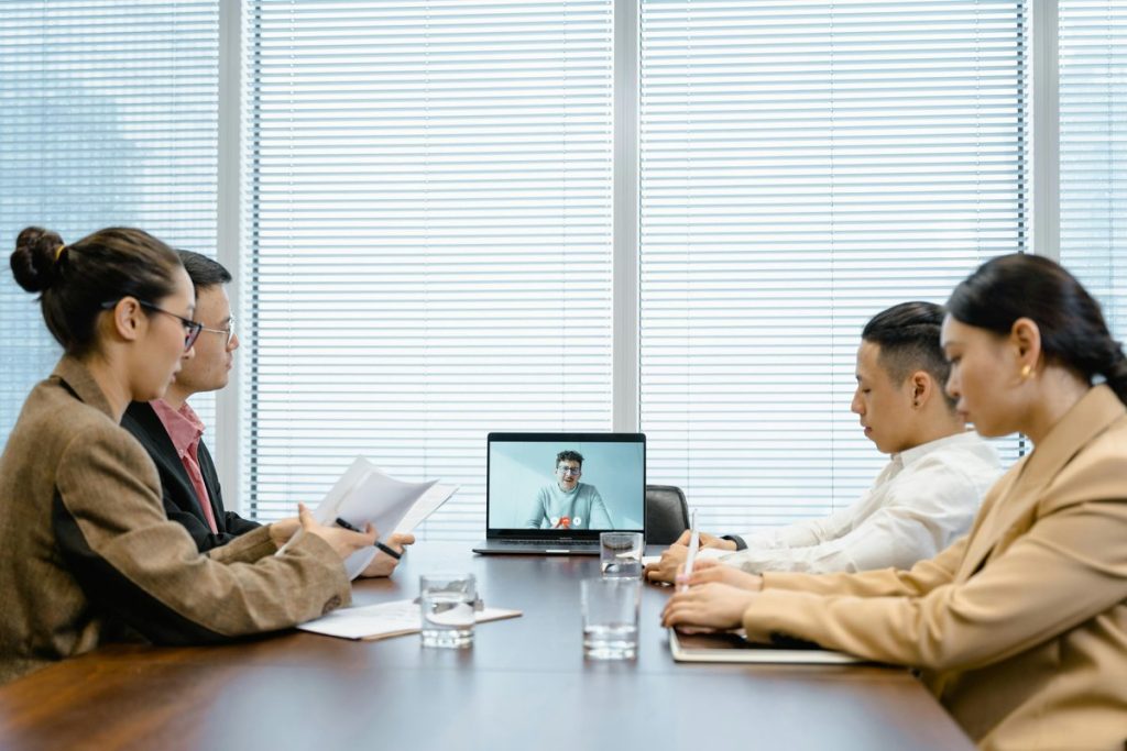 Executives in boardroom meeting with remote participant on video conference call
